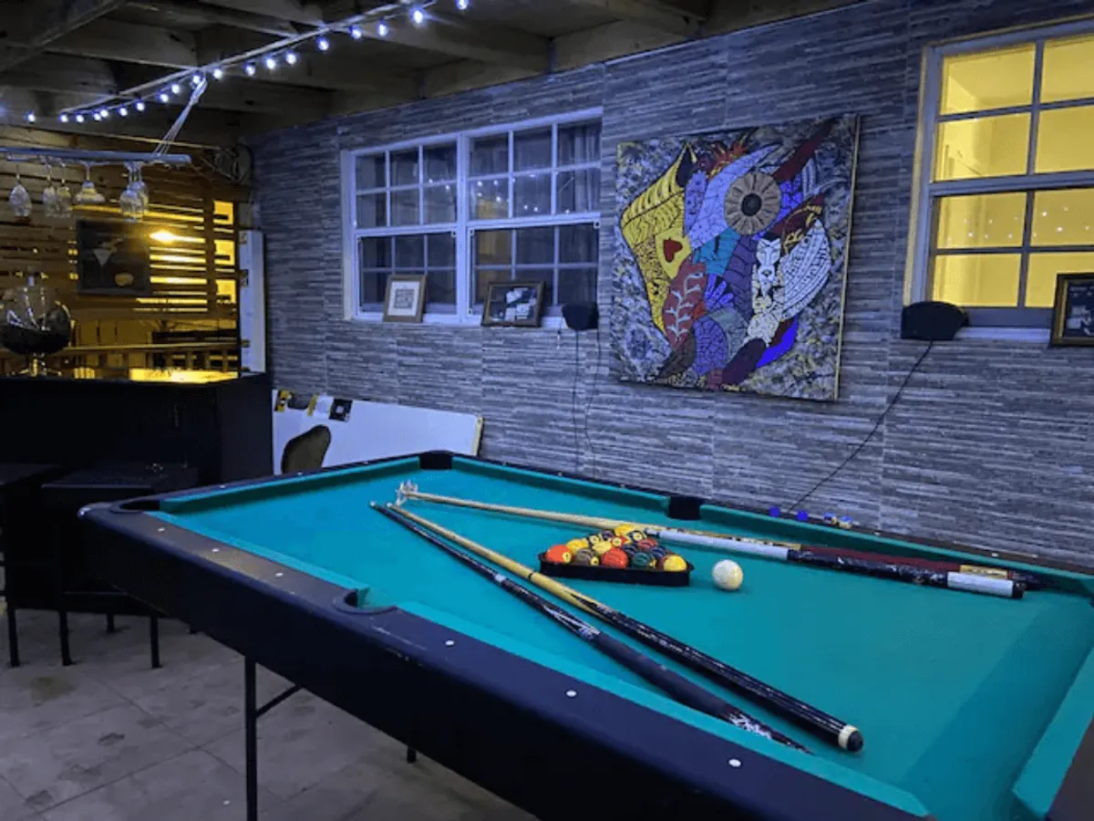 An inviting interior view of the villa’s entertainment space featuring a pool table, colorful artwork, and a bar area. The setting is perfect for friendly competition and lively social gatherings with friends.
